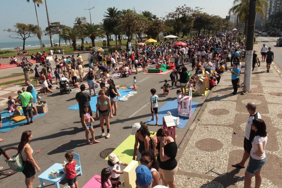 crianças e adultos brincam na avenida da praia. #paratodosverem 