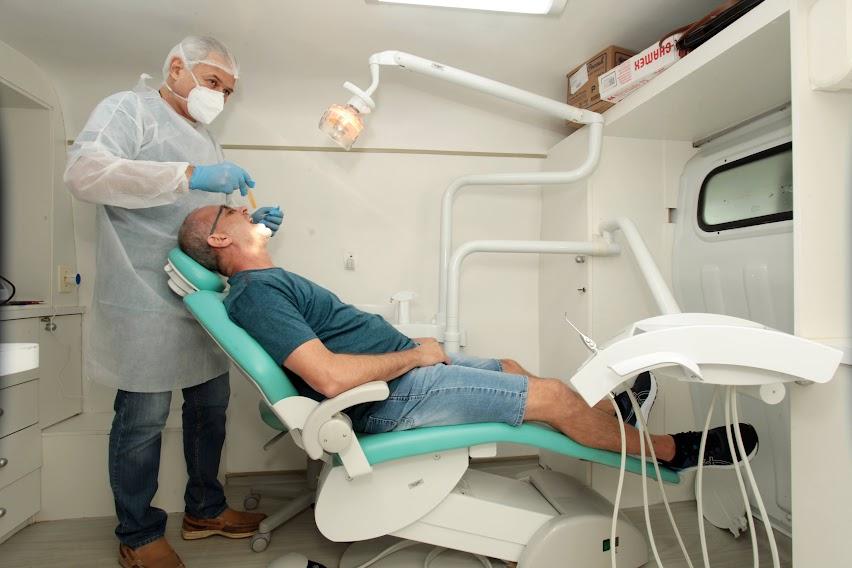 dentista atende homem que está na cadeira do consultório móvel. #paratodosverem