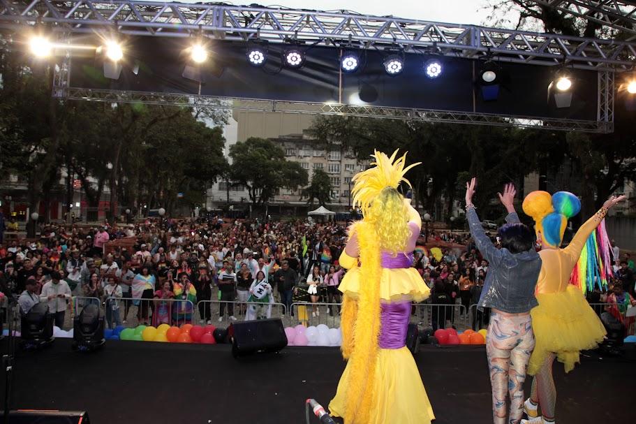pessoas na praça acompanhando show com pessoas fantasiadas no palco #paratodosverem
