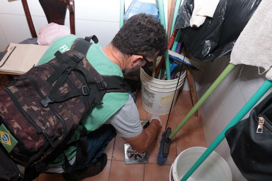 homem agachado fiscaliza ponto de uma casa #paratodosverem