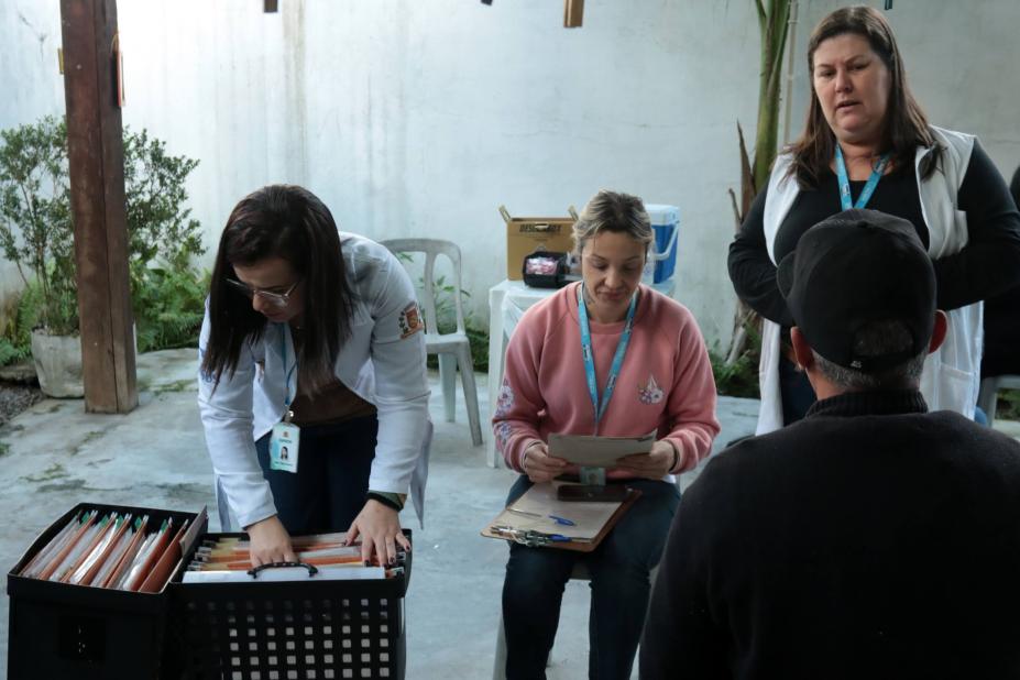 agentes de saúde atendem pessoas em salão. #paratodosverem