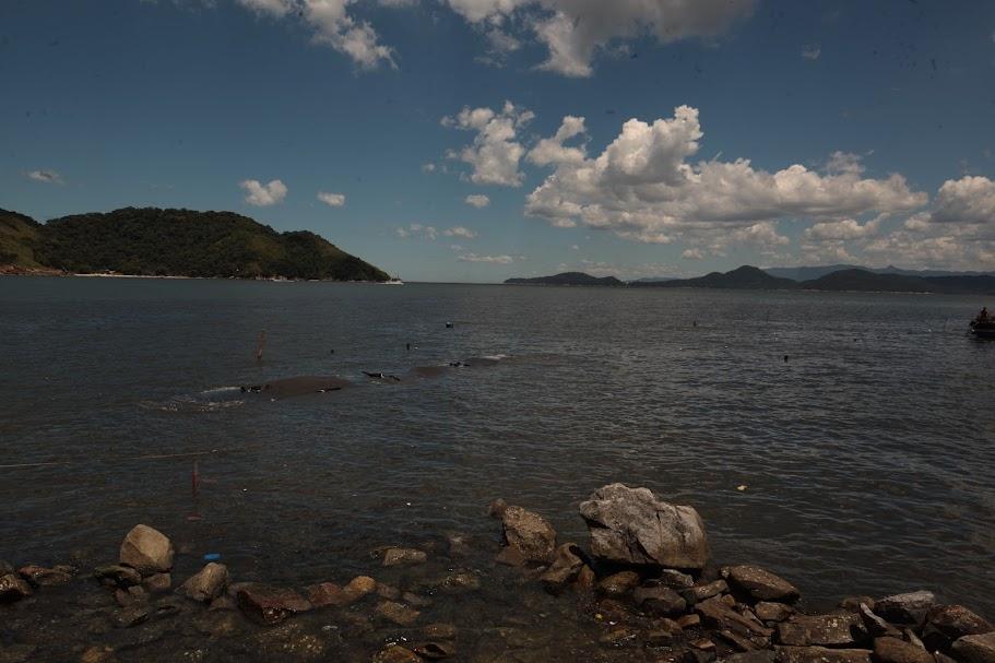 vista do mar com pedras em primeiro plano e geobag ao fundo. #paratodosverem 