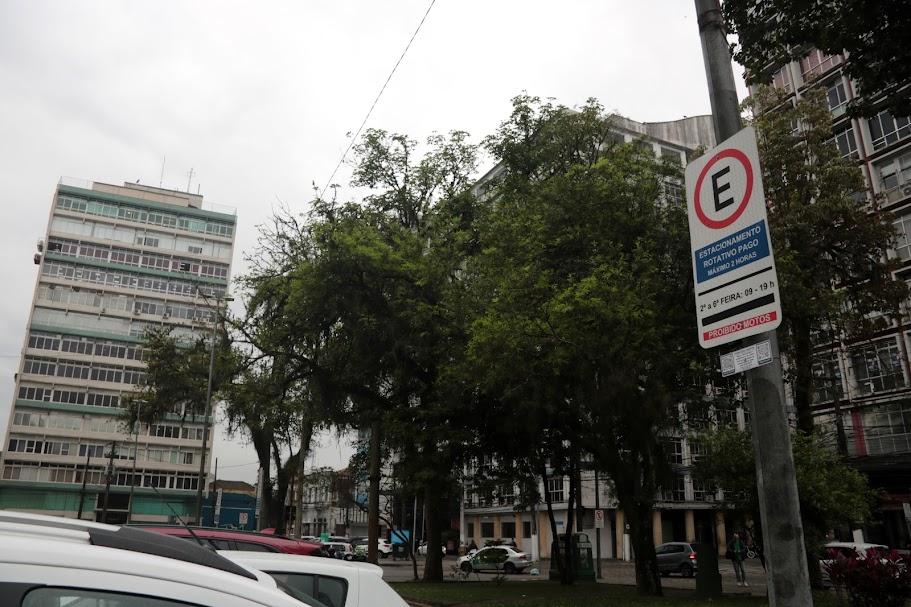 placa de zona azul em posto. há carros na rua. Ao fundo se vê árvores e prédios. #paratodosverem 