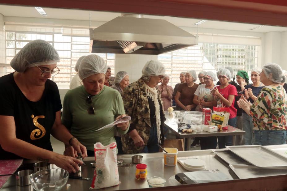 mulheres em torno de fogão industrial em aula de culinária. #paratodosverem