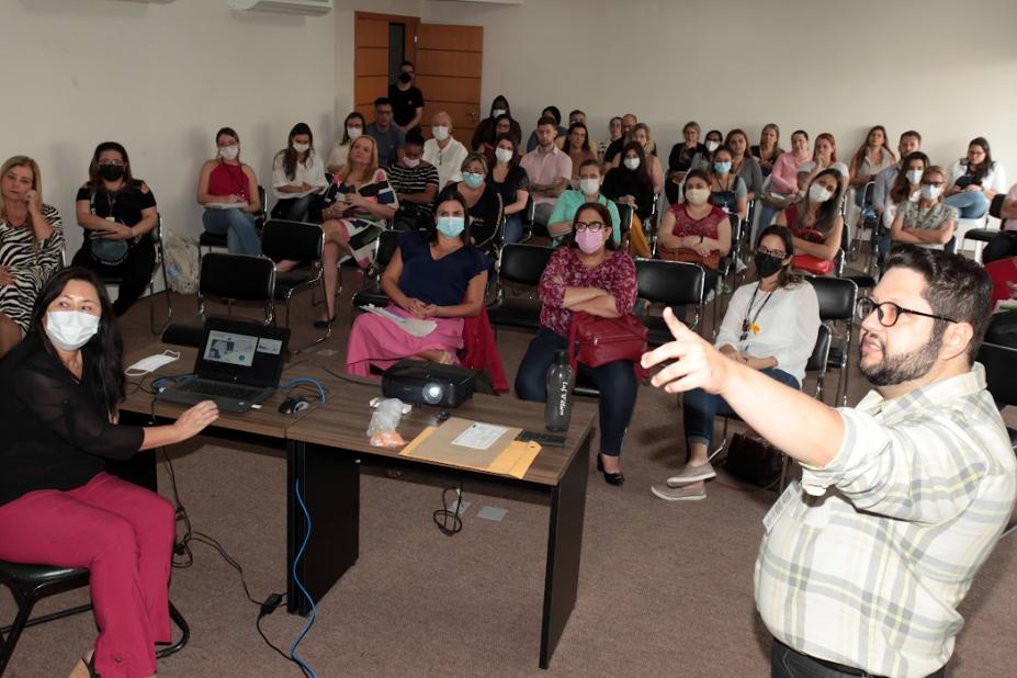 palestrante fala e pessoas sentadas em auditório acompanham #paratodosverem