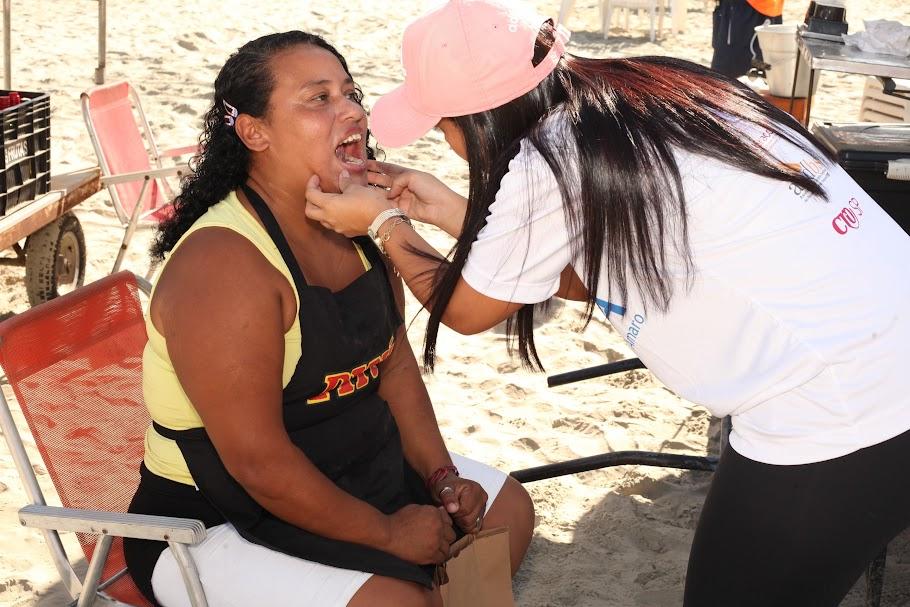 DENTISTA EXAMINA BOCA DE MULHER QUE ESTÁ SENTADA EM CADEIRA DE PRAIA. #PARATODOSVEREM