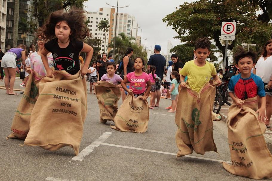 crianças brincam de pula-saco na avenida da praia. #paratodosverem