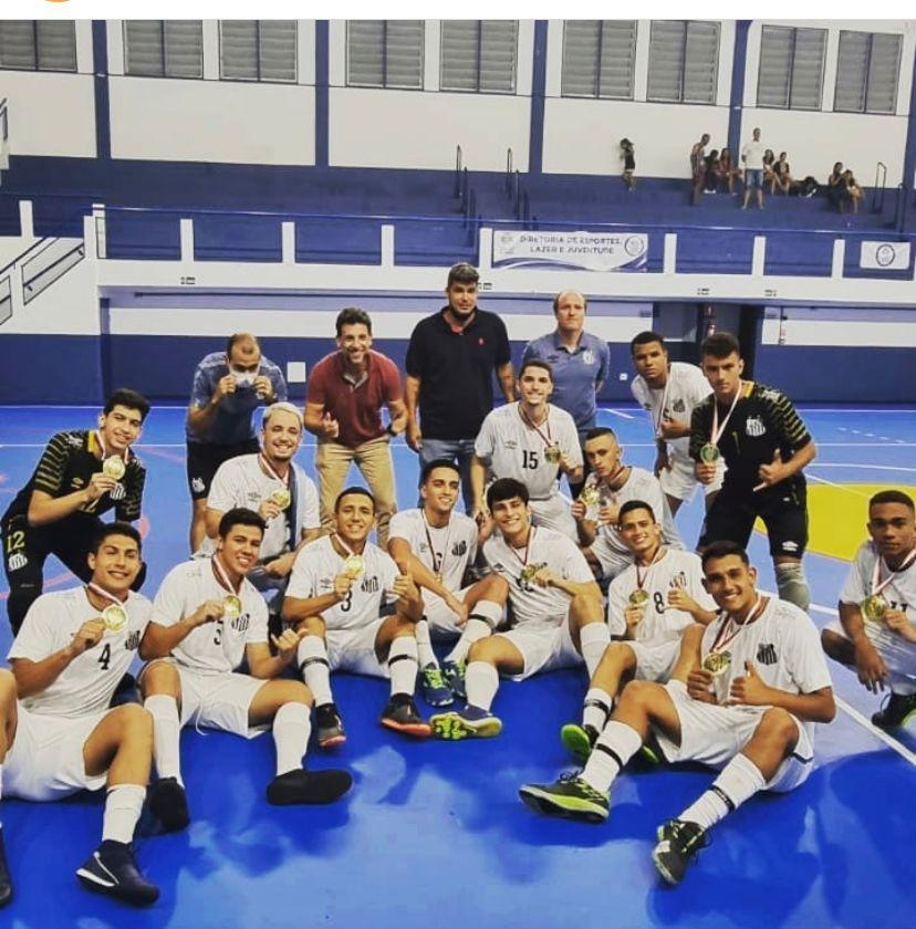 Jogadores de futsal com medalhas sentados na quadra #paratodosverem