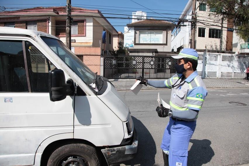 Agente da CET segura folheto diante de van para prender no para-brisa