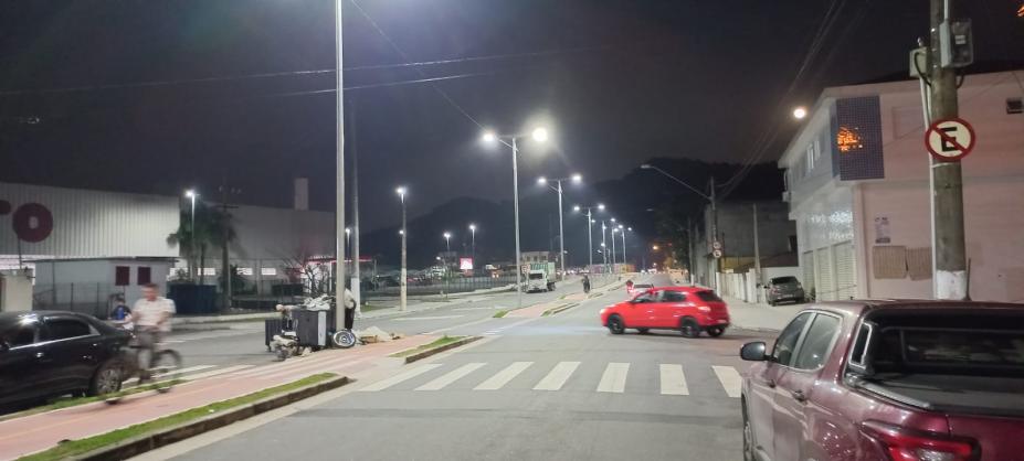 vista geral de avenida com luminárias de postes acesas à noite. #paratodosverem