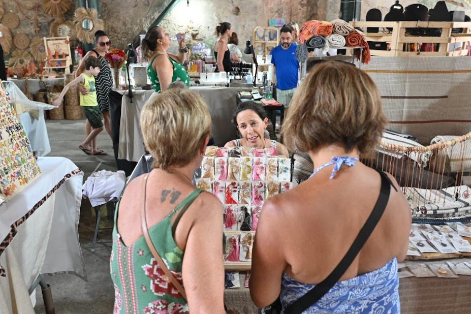 Mulheres observam estande com artesanato. #pratodosverem