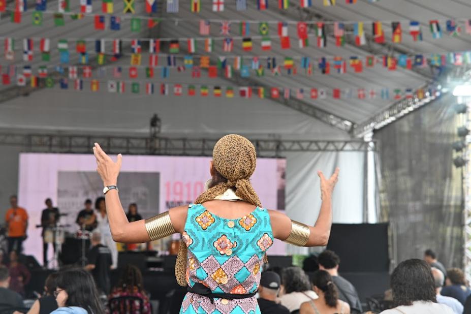 pessoa em pé, de costas para um palco #paratodosverem