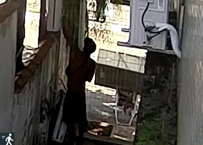 homem está de costas trepado em muro de unidade de saúde. #paratodosverem