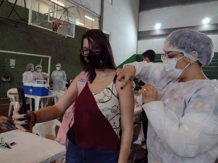 Jovem tira foto ao mesmo tempo q recebe a vacina. #paratodosverem