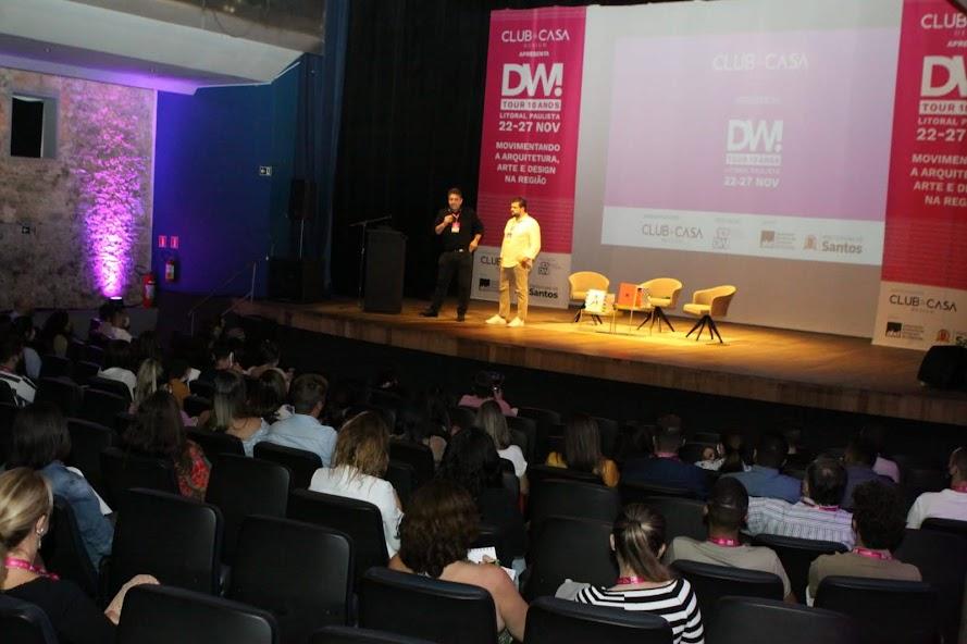 plateia assiste a dois rapazes no palco na abertura do evento #paratodosverem