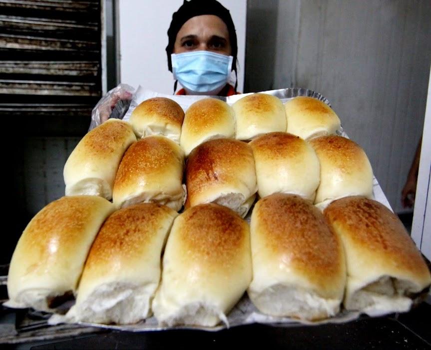 mulher com mascara mostra fornada com pão de cará. #paratodosverem