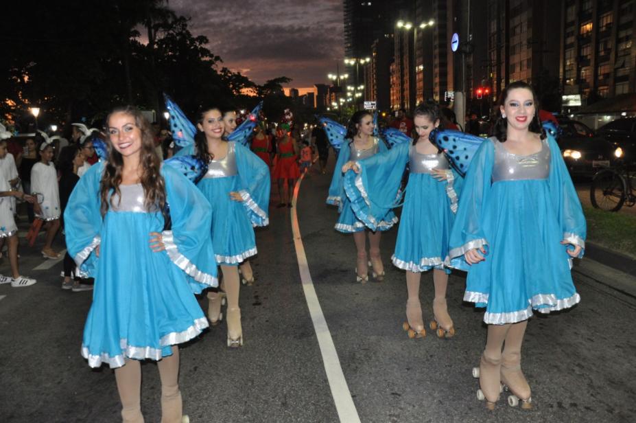 patinadoras andam por avenida vestidas com vestidos que têm asas, como borboletas. #paratodosverem 