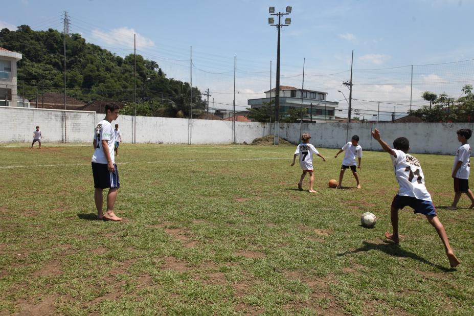 #pracedover No campo do centro esportivo, menino com uniforme de futebol se prepara para chutar bola em direção ao gol