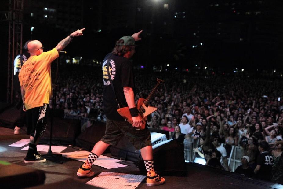 cantores estão no palco se apresentando. Grande público ao fundo. #paratodosverem