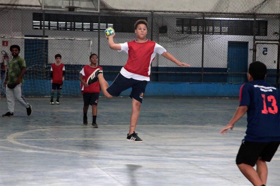 menino está com a bola na mão pronta para lançar. ele está dando um salto, flutuando no ar. #paratodosverem 