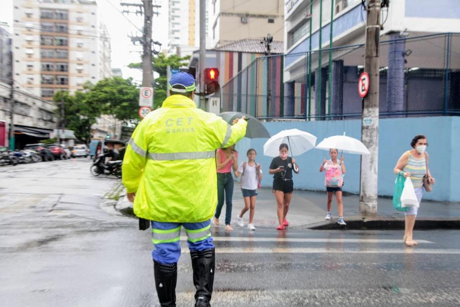 agente da CET está de costas para a foto fazendo sinal para pessoas atravessarem na faixa. #paratodosverem