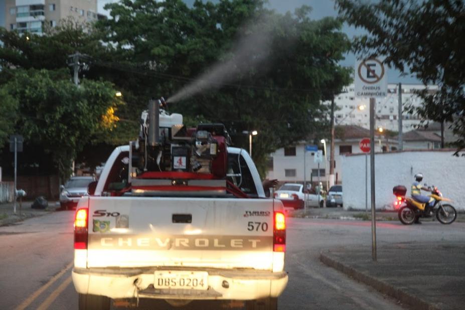 Carro ao centro dispersando inseticida em rua de Santos. #paratodosverem