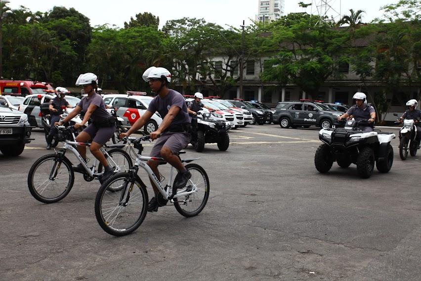 Policiais em bicicletas, quadriciclos e viaturas ao fundo #paratodosverem