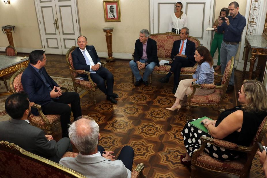 grupo de pessoas sentadas em um amplo salão #paratodosverem