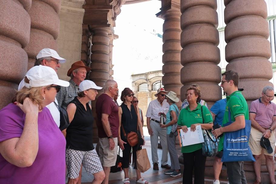 turistas estão parados junto a guias na entrada do museu do café. #paratodosverem 