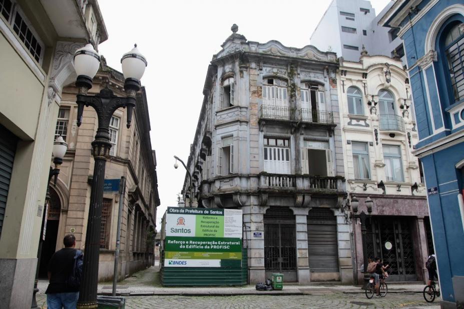 fachado do prédio com placa da obra ao lado #paratodosverem