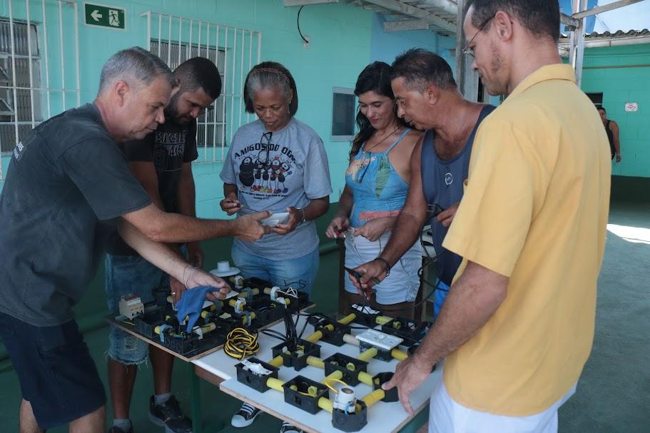 alunos adultos em torno de uma mesa com material elétrico. #paratodosverem 