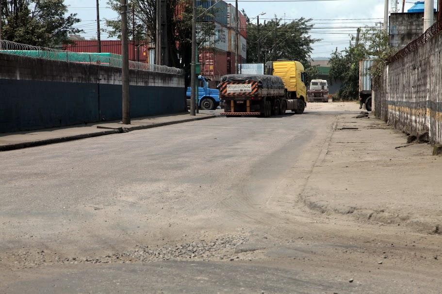rua asfaltada com desnível em primeiro plano. Ao fundo, um caminhão. #paratodosverem