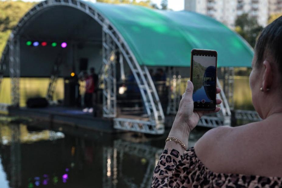 mulher está segurando celular e filmando palco na lagoa da saudade. #paratodosverem 