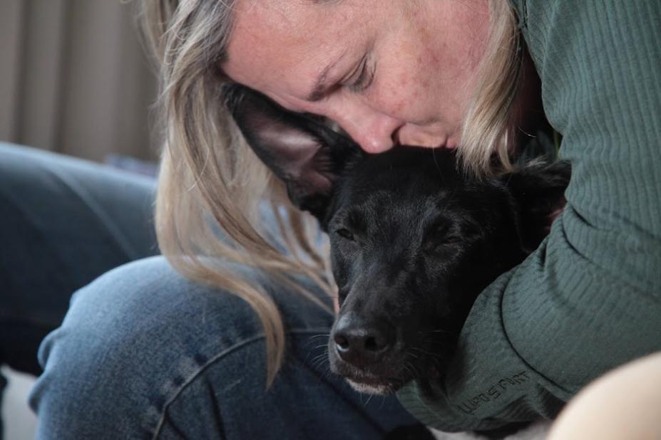 mulher abraça e beija cão na cabeça. Os dois estão de olhos fechados. #paratodosverem