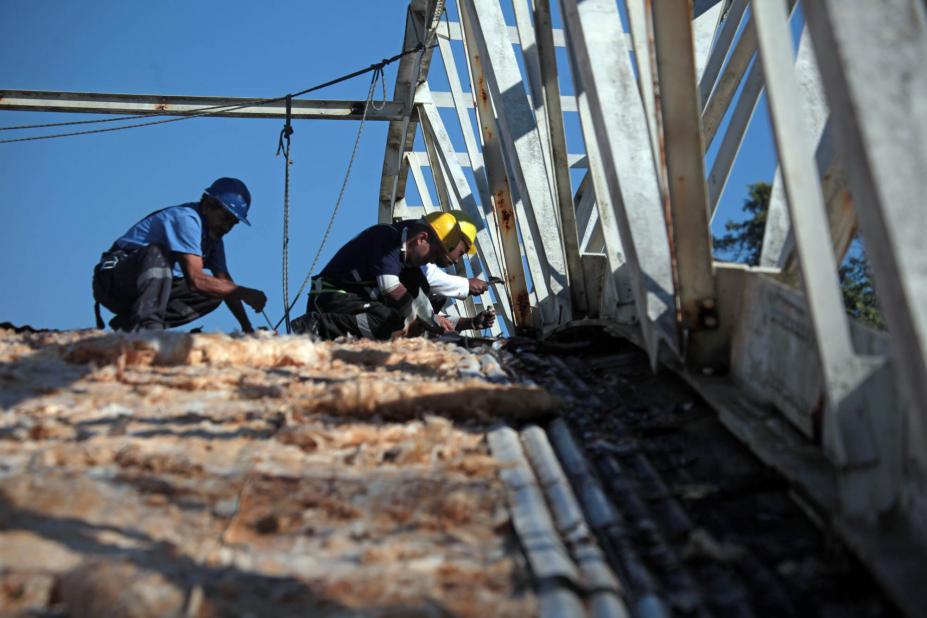 Homens trabalham na recuperação de telhado. #Pracegover