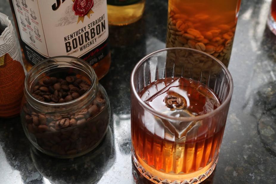 vidro com grãos de café e copo com whiskey. #paratodosverem