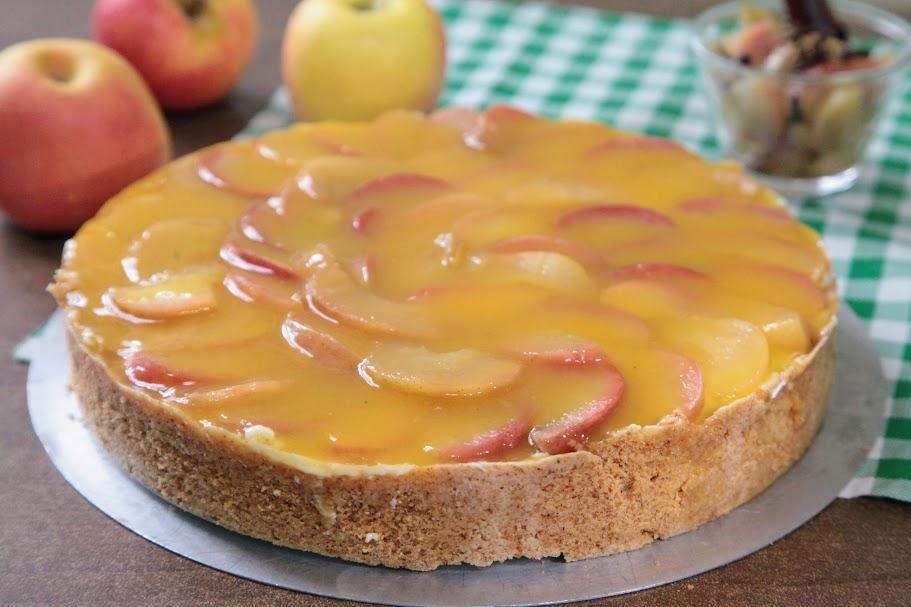 torta de mação sobre uma mesa com maçãs in natura ao fundo. #paratodosverem 