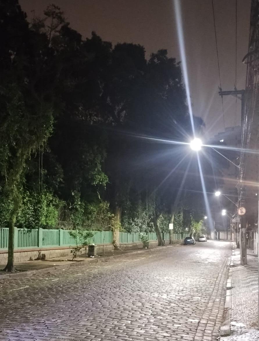 rua à noite com ponto de luz reluzindo no alto e ao fundo. #paratodosverem 