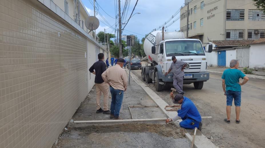 homens trabalham na construção de calçadas. Há um caminhhão de concreto parado na rua. #paratodosverem 