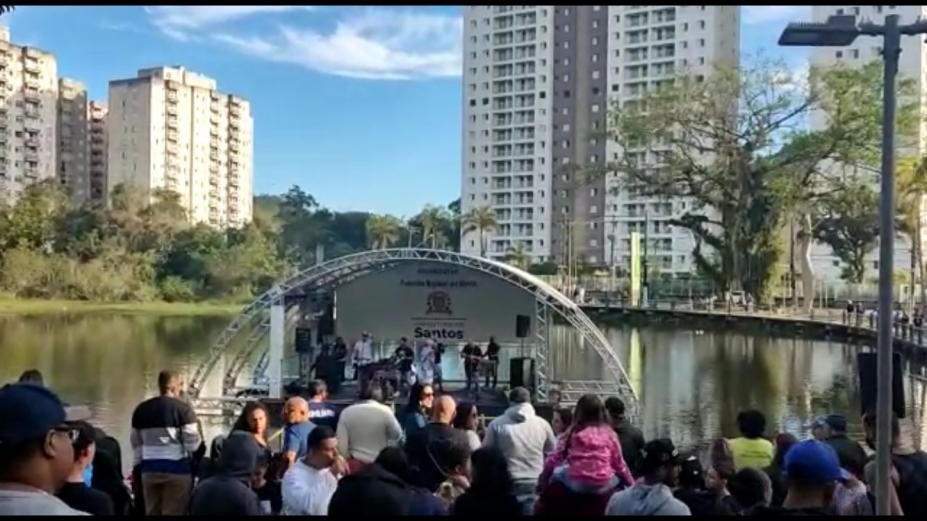 público em primeiro plano, de costas, assistindo apresentação em palco flutuante. #paratodosverem