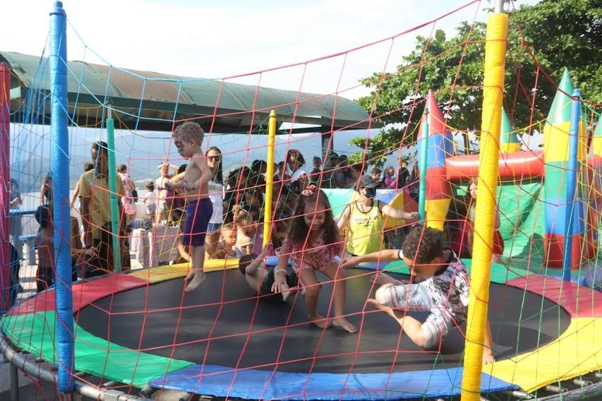 crianças brincam em pula-pula cercado por rede. #paratodosverem