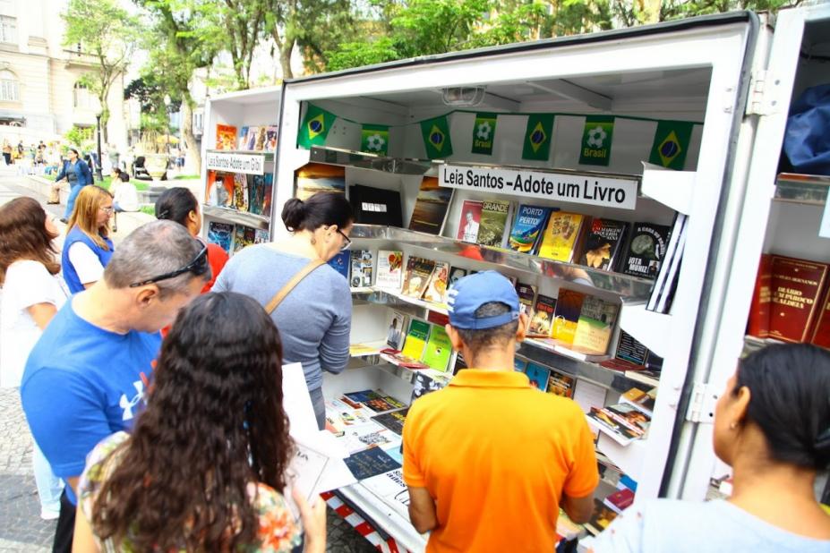 estande do projeto com vários livros dispostos e pessoas em torno. #paratodosverem