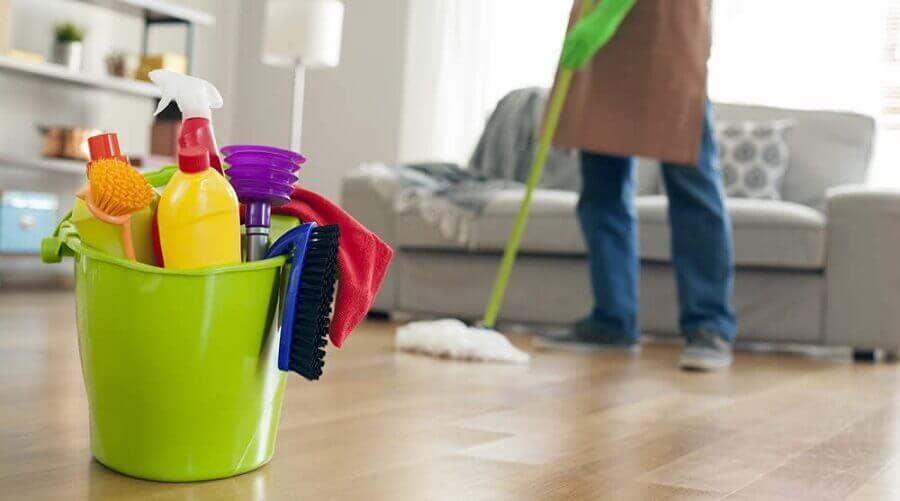 pessoa limpando chão de casa com produtos na frente em balde #paratodosverem
