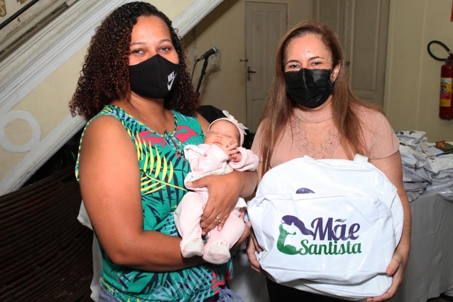 MULHER COM BEBE NO COLO ESTÁ AO LADO DE OUTRA QUE SEGURA UMA BOLSA COM KIT PARA MÃE E BEBE. #PARATODOSVEREM