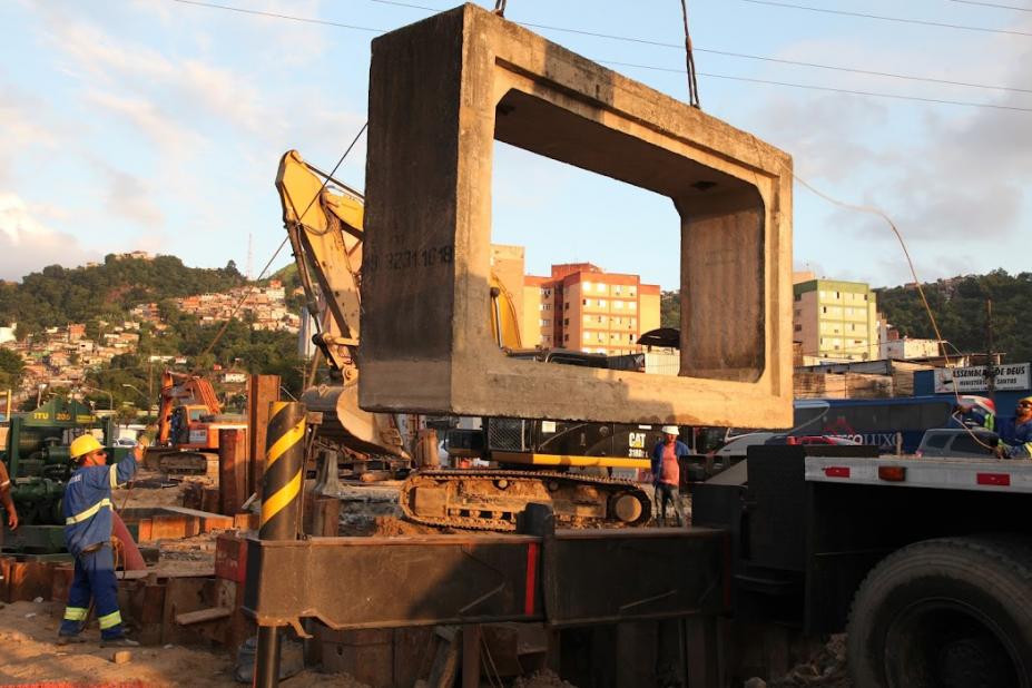 obra de macrodrenagem com grande aduela suspensa no ar. #paratodosverem