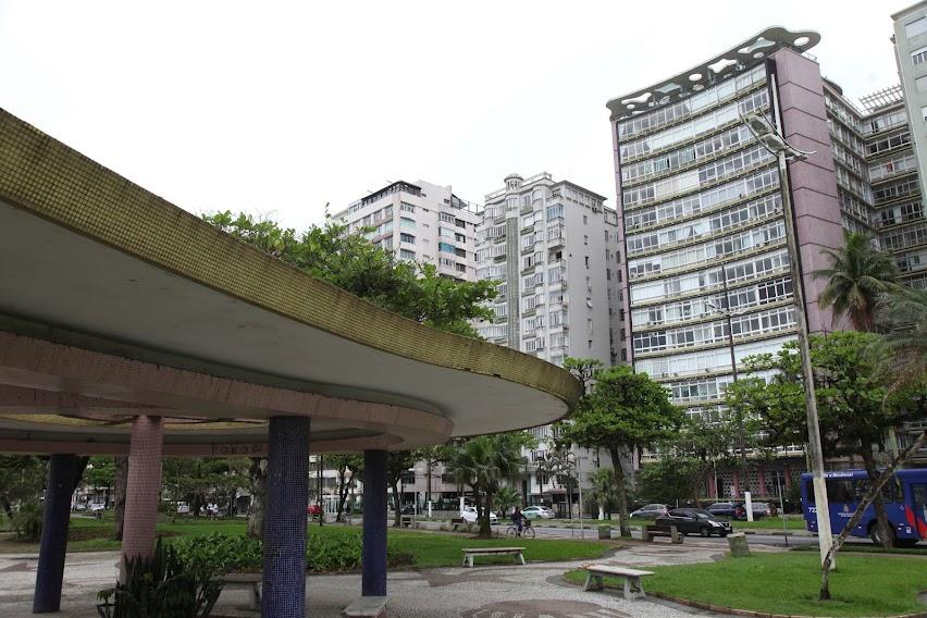 pérgola no jardim da orla, com edifício verde mar ao fundo. #paratodosverem