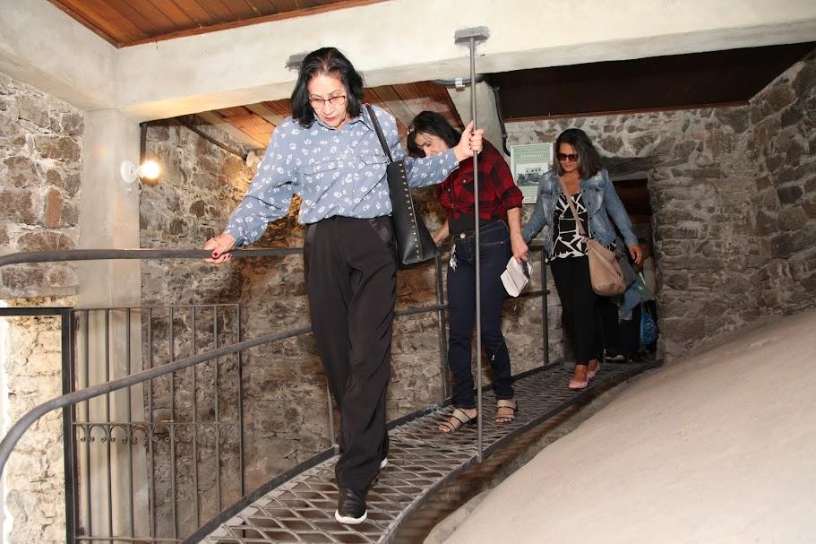 Três mulheres caminham em passsarela dentro de uma espécie de gruta. #paratodosverm 