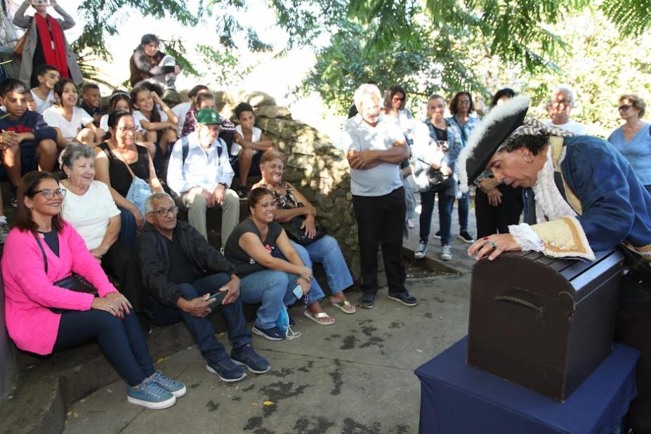 pirata está mexendo em baú diante de plateia que está sentada. #paratodosoverem 