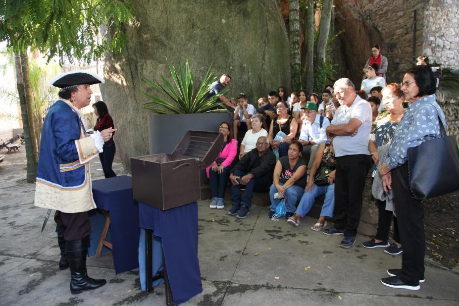 personagem de pirata diante de caixa fala com visitantes. #paratodosverem
