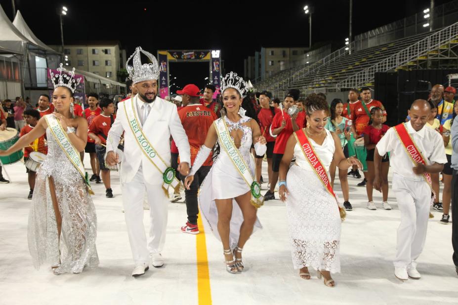 os integrantes da corte carnavalesca, em cinco pessoas, desfilam na passarela do samba. #paratodosverem 